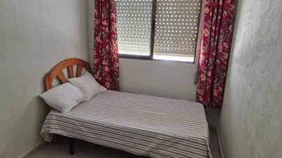 a small bed in a room with a window at Apartment in Rota Cadiz, terrace AC wifi in Rota
