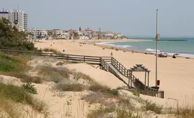 a beach with people walking on the sand at Apartment in Rota Cadiz, terrace AC wifi in Rota