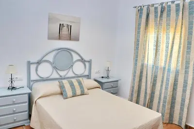 a bedroom with a bed with a mirror and a window at Chalet Chaparrillo Conil in Conil de la Frontera