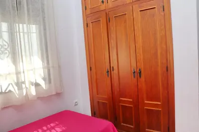 a bedroom with a wooden cabinet next to a window at Chalet Chaparrillo Conil in Conil de la Frontera