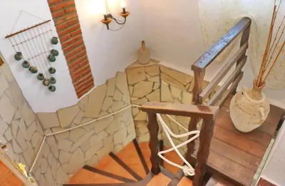 a staircase with a stone wall and a wooden chair at Apartamento Chinarejo in Conil de la Frontera