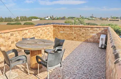 a patio with a table and chairs and a brick wall at Apartamento Chinarejo in Conil de la Frontera