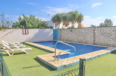 a swimming pool in a yard with chairs and a fence at Apartamento Chinarejo in Conil de la Frontera
