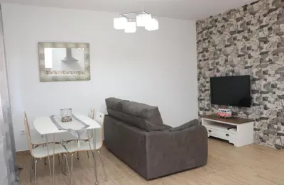 a living room with a couch and a table and a television at Apartamento en Conil con piscina in Conil de la Frontera