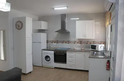 a kitchen with white cabinets and a stove top oven at Apartamento en Conil con piscina in Conil de la Frontera