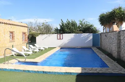 a swimming pool with chairs next to a fence at Apartamento en Conil con piscina in Conil de la Frontera