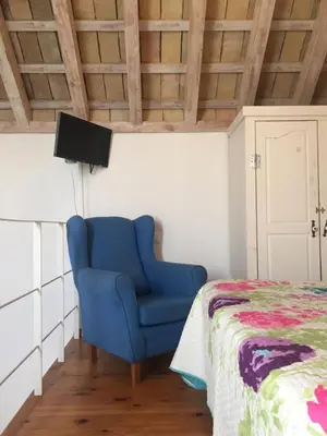 a blue chair in a room with a bed at La Casa de Abu - Casita con Encanto in Medina Sidonia