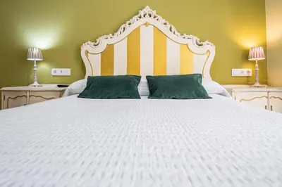 a large white bed with two green pillows on it at Caleta Beach in Cádiz