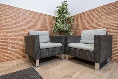 two wicker chairs sitting next to a brick wall at Caleta Beach in Cádiz