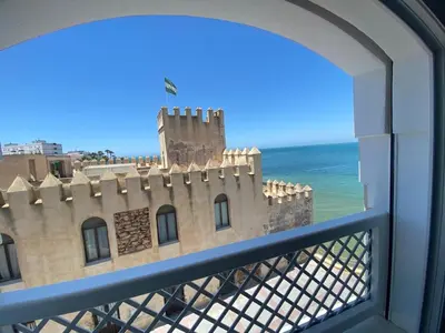 a balcony with flags and the ocean in the background at Hotel La Española in Chipiona