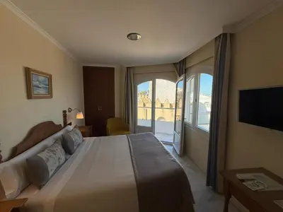 a bedroom with two beds and a large window at Hotel La Española in Chipiona