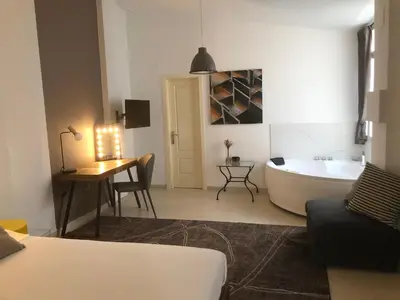 a bathroom with a tub and a bed and a table at Apartamentos Las Naranjas in Jerez de la Frontera