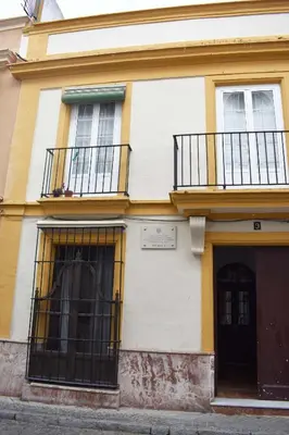a yellow and white building with two windows at Apartamentos Las Naranjas in Jerez de la Frontera