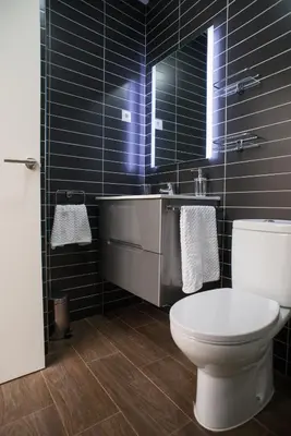 a black tiled bathroom with a toilet and a sink at La Posada del Mercado in Cádiz
