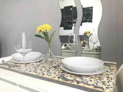a table with plates and glasses and a vase with flowers at Apartamento Conocedores in Jerez de la Frontera