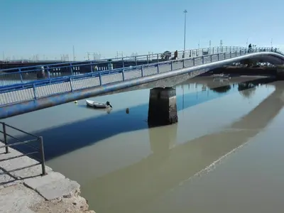 a bridge over a river with a boat in the water at Apartamento Valdelagrana in El Puerto de Santa María