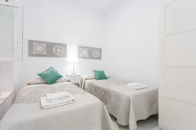 two beds in a white room with green pillows at Casa TANGUILLOS de Cadiz in Cádiz