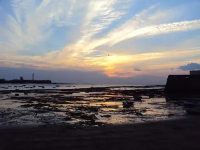a sunset on a beach with the sun setting at Casa TANGUILLOS de Cadiz in Cádiz