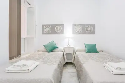 two beds in a white room with green pillows at Casa TANGUILLOS de Cadiz in Cádiz