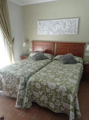 a bedroom with two beds with green blankets at Hostal Costa Luz in El Puerto de Santa María