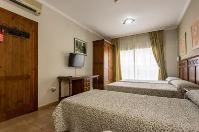 a hotel room with two beds and a television at Hostal Costa Luz in El Puerto de Santa María