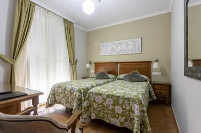 a bedroom with a bed and a desk and a window at Hostal Costa Luz in El Puerto de Santa María