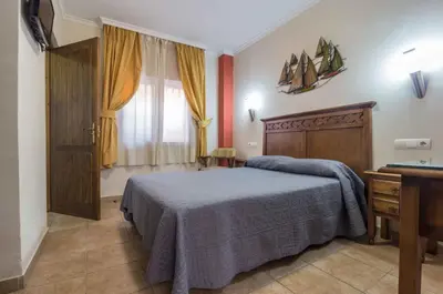 a bedroom with a bed and a desk and a window at Hostal Costa Luz in El Puerto de Santa María