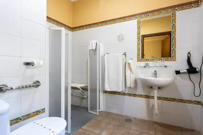 a bathroom with a sink and a toilet and a mirror at Hostal Costa Luz in El Puerto de Santa María