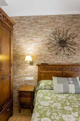 a bedroom with a bed and a brick wall at Hostal Costa Luz in El Puerto de Santa María