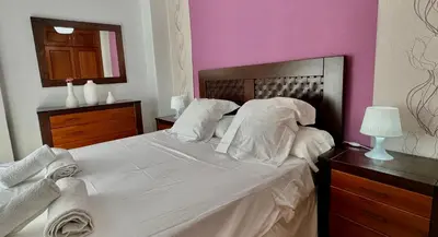 a bedroom with a white bed and a pink wall at SibsSanlucar Reina 2 del Centro Parking in Sanlúcar de Barrameda