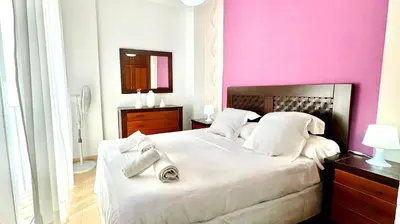 a bedroom with a white bed and a pink wall at SibsSanlucar Reina 2 del Centro Parking in Sanlúcar de Barrameda