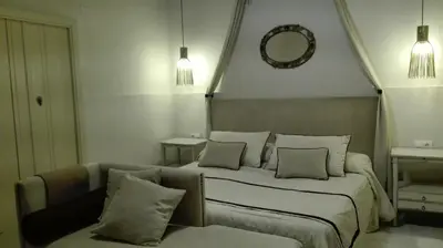 a bedroom with a bed and a couch and a mirror at Estudio Bizcocheros in Jerez de la Frontera
