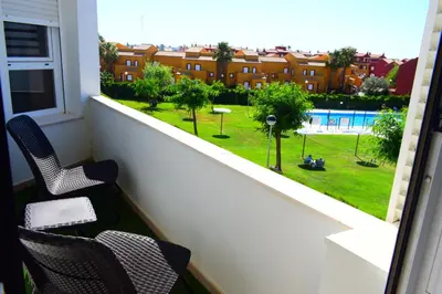 a balcony with two chairs and a view of a pool at Apartamento Costa Ballena con WIFI in Rota