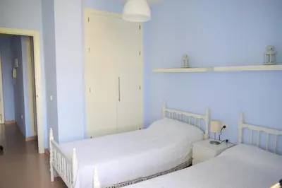 two twin beds in a bedroom with blue walls at Apartamento Costa Ballena con WIFI in Rota