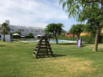 a wooden ladder sitting in the grass near a pool at Apartamento Costa Ballena con WIFI in Rota