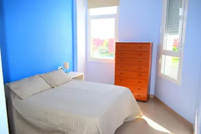 a blue and white bedroom with a bed and a dresser at Apartamento Costa Ballena con WIFI in Rota