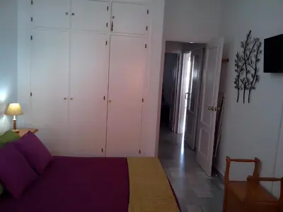 a bedroom with a bed with purple sheets and white cabinets at Apartamento Pepi Chipiona in Chipiona