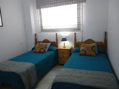 a bedroom with two beds and a window at Apartamento Pepi Chipiona in Chipiona