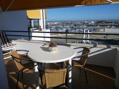 a table and chairs on a balcony with a view of a harbor at Apartamento Pepi Chipiona in Chipiona