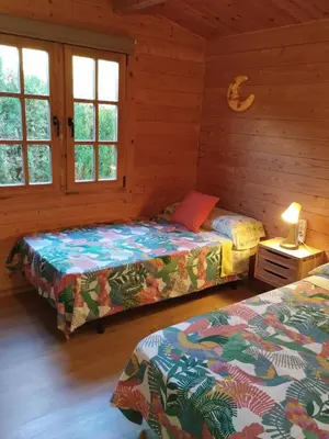 a bedroom with two beds in a log cabin at Cabaña Blanca Roche Jorge in Conil de la Frontera