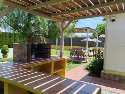 a patio with a wooden pergola and an outdoor grill at Cabaña Blanca Roche Jorge in Conil de la Frontera