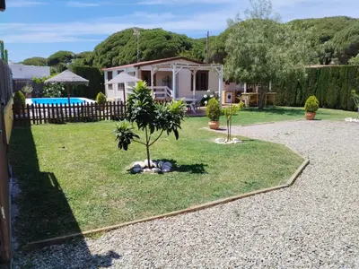 a dog laying in the grass in front of a house at Cabaña Blanca Roche Jorge in Conil de la Frontera