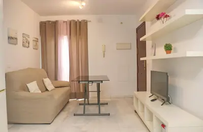 a living room with a couch and a table and a tv at Apartamento Andujar in Cádiz