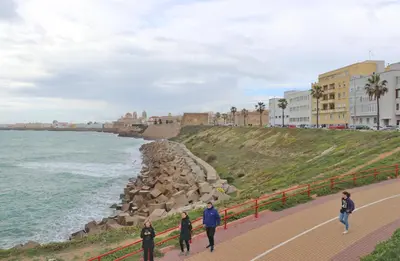 a group of people walking along a sidewalk near the ocean at Apartamento Andujar in Cádiz