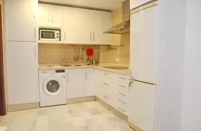 a kitchen with white cabinets and a washer and dryer at Apartamento Andujar in Cádiz