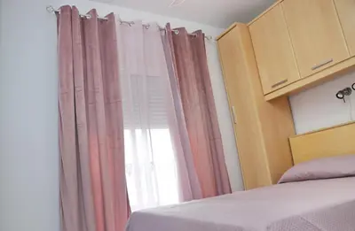 a bedroom with a bed and a window with curtains at Apartamento Andujar in Cádiz