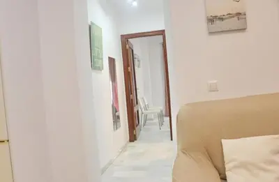 a bedroom with a bed and a hallway with a chair at Apartamento Andujar in Cádiz