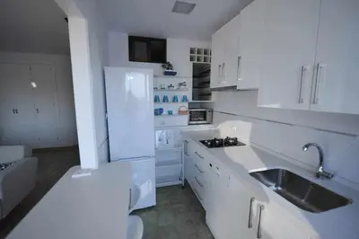 a white kitchen with a sink and a refrigerator at Atico Apartamento Loft Playa Victoria Cadiz in Cádiz