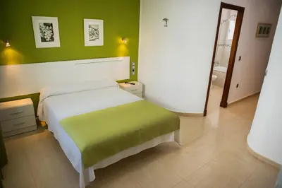 a bedroom with a bed and a green wall at Hostal Victoria Mar in Chipiona
