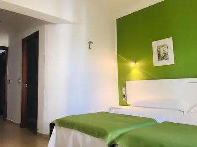 a bedroom with two beds and a green wall at Hostal Victoria Mar in Chipiona